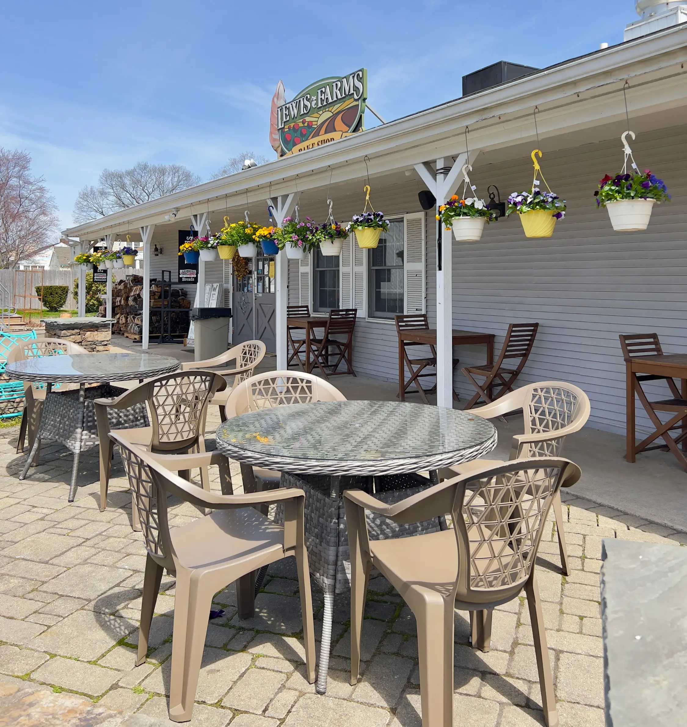 Outdoor patio tables and chairs by the Lewis Farms porch with hanging flower baskets
