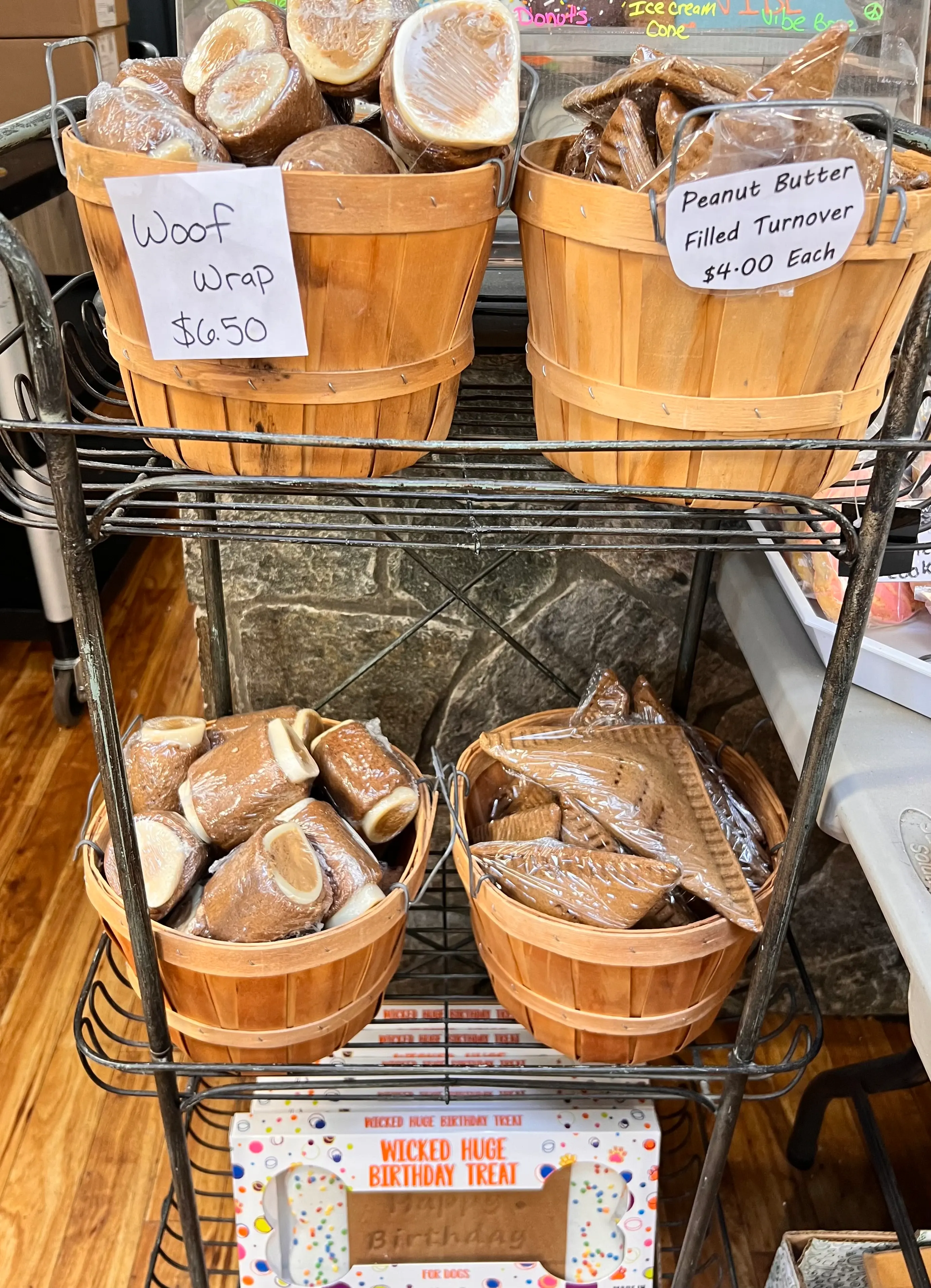 Baskets of dog treats with signs: Woof Wrap $6.50, Peanut Butter Filled Turnover $4.00 Each